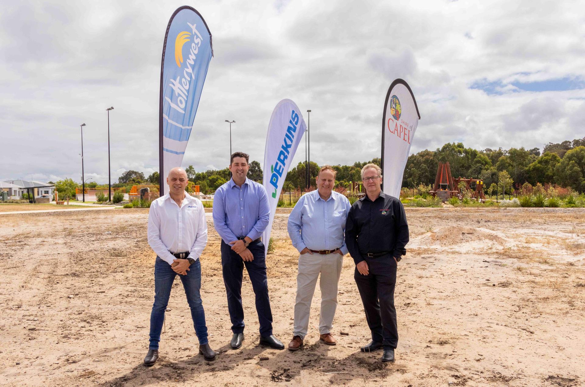 four men standing on site with flags in the background